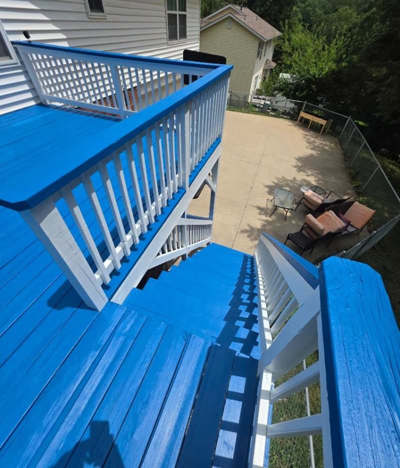 Deck repairing project featuring a bright blue wooden deck, matching stairs, white railings, and an elevated outdoor patio area.